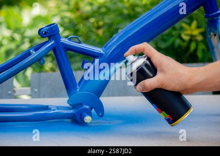 Spray Painting a Bicycle Frame Outdoors. Stock Photo