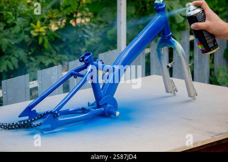 Spray Painting a Bicycle Frame Outdoors. Stock Photo