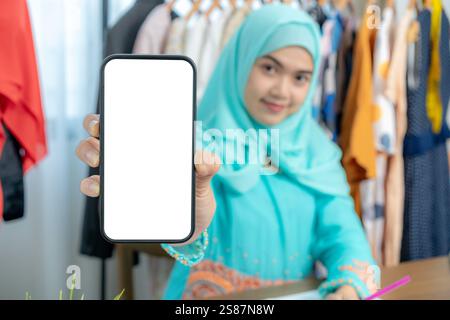 A female tailor showing a smartphone screen that is blank and ready for text input. Stock Photo