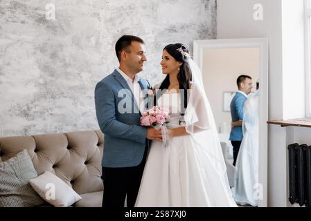 groom in a blue suit with a bow tie and the bride in a tight white dress in a bright studio Stock Photo