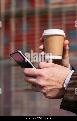 hands of man with coffee and browsing mobile phone Stock Photo