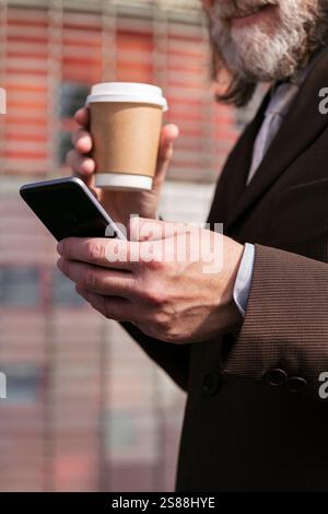 hands of man with coffee and using mobile phone Stock Photo