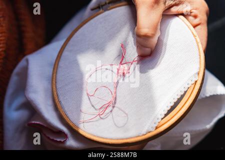 close up of woman hands embroidering using embroidery hoop and sewing kit on canvass. concept of at home craft activity Stock Photo