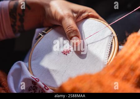 close up of woman hands embroidering using embroidery hoop and sewing kit on canvass. concept of at home craft activity Stock Photo