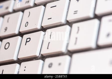 Close-up view of a section of a white computer keyboard.  The image shows various keys, including the letter "P",  and other characters like "0", "=", Stock Photo