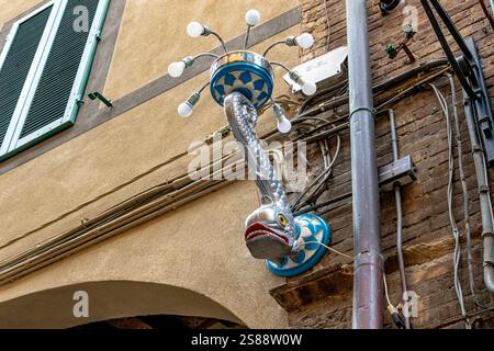 A decorative street lamp representing the Contrada of the Wave, Contrada Onda on a street wall in Siena ,Italy Stock Photo
