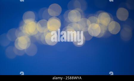 Abstract golden lights of blue background with bokeh and illuminated christmassy festive lighting for new year. Stock Photo