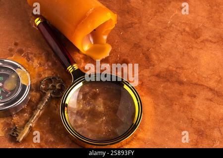 Old compass, key, magnifying glass and candle on brown background Stock Photo