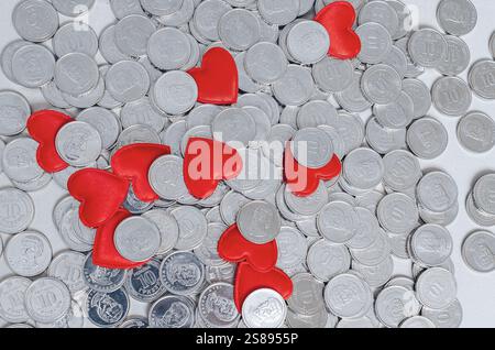 Scattered silver coins and several red hearts isolated on grey. Valentine's Day card. Idea for design Stock Photo