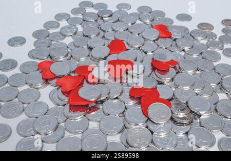 Scattered silver coins and several red hearts isolated on grey.  Idea for design. Valentine's Day card Stock Photo