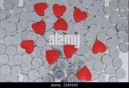 Several red hearts, scattered silver coins isolated on grey. Valentine's Day card. Idea for design Stock Photo