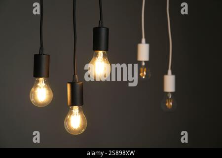 Light bulbs hanging on cords against grey background, selective focus Stock Photo