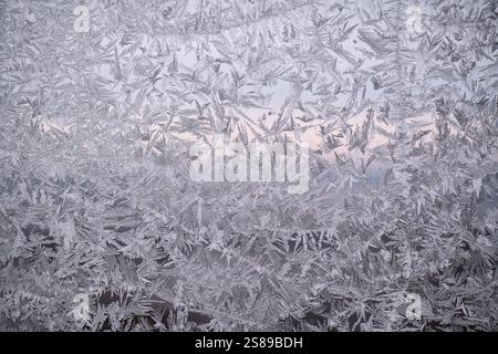 Winter frost on windows with sun pouring in and illuminating the ice, close-up detailed abstract image. Stock Photo