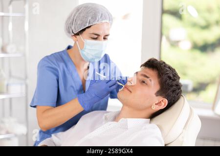 Young man having face care by means of injection in aesthetic clinic Stock Photo