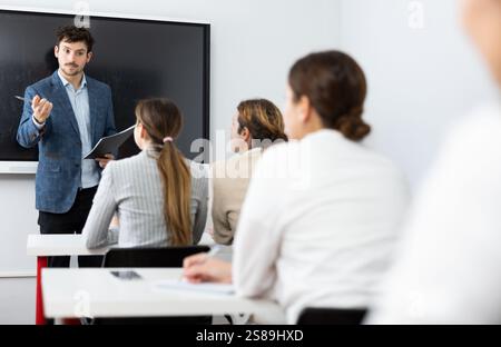 Young male teacher giving lecture to group of student Stock Photo