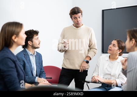 Competent male tutor teaching students in college classroom Stock Photo