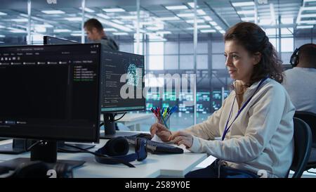 Joyful technician working in high tech workspace providing computing resources for different workloads. Relaxed woman tasked with monitoring data center supercomputers, camera B Stock Photo