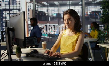 Portrait of smiling programmer creating machine learning models that can process and analyze data to automate decision making processes. Cheerful IT professional programming in office, camera B Stock Photo