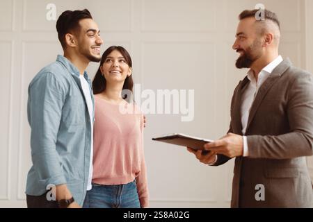 Couple Buying New Apartment Talking With House Agent Stock Photo