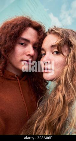 Young couple looking at camera seriously, standing together outdoors. Stock Photo