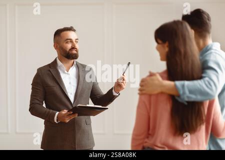 Couple Buying New Apartment Talking With House Agent Stock Photo