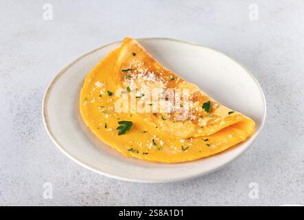 Plain egg omelette with parmesan cheese and parsley on grey background.  Stock Photo