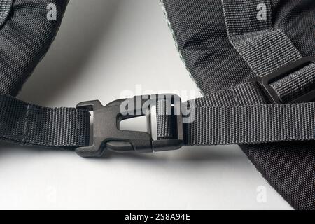 close-up of attached quick release black plastic buckle on shoulder strap of backpack on white surface background Stock Photo