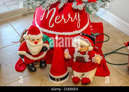 Small Mr. & Mrs. Santa Clause Sitting In Front Of Tree Stock Photo
