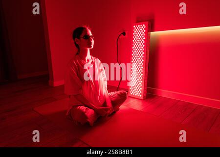 A young woman wearing protective eyewear during a red light therapy session Stock Photo