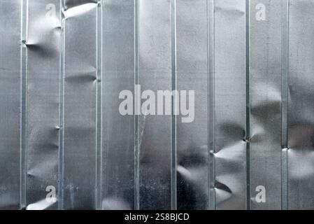 Textured metallic surface with vertical panel lines and visible dents, offering an industrial aesthetic. The image emphasizes symmetry, durability, an Stock Photo