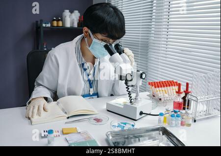 Scientist Analyzing Samples Under Microscope in Laboratory Stock Photo