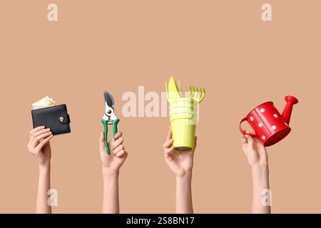 Female hands with gardening tools and wallet on color background Stock Photo