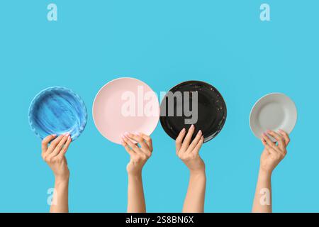Hands holding empty plates on blue background Stock Photo