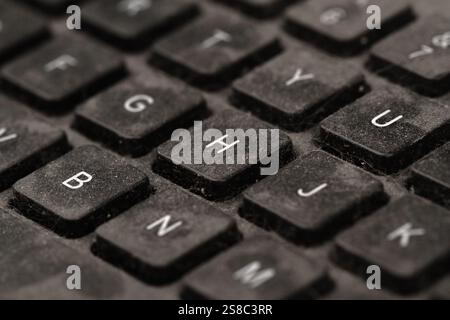 front view closeup of old black keyboard with keys covered in dust and dirt isolated on white background Stock Photo