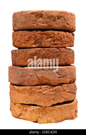 Pile of ancient weathered millstones arranged in a stack isolated on a white background Stock Photo