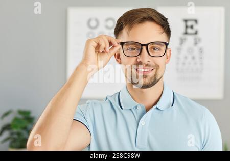 Portrait of a young cheerful smiling male patient standing in ophthalmology clinic. Stock Photo