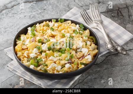 Spicy Mexican corn potato salad with hard boiled eggs, onions and pickled jalapenos and cheese close-up in a plate on the table. horizontal Stock Photo