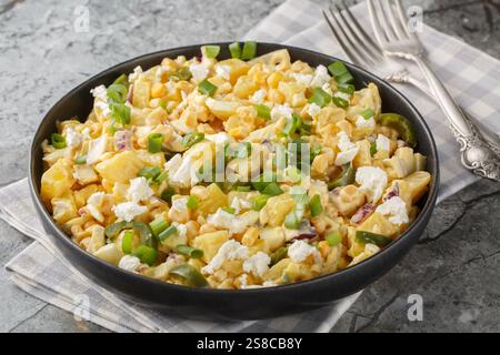 Mexican Corn Potato Salad made with corn kernels in a creamy mixture of mayonnaise, sour cream, cheese closeup on the plate on the table. Horizontal Stock Photo