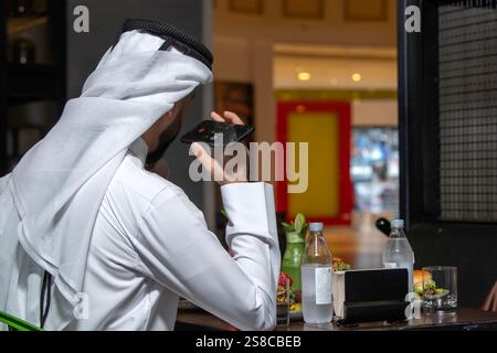 Young Arab Man holding phone in restaurant. back view Stock Photo