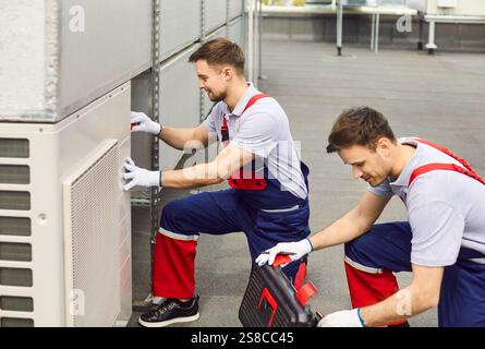 Air conditioning technicians are repairing and maintaining air conditioners on the roof. Stock Photo