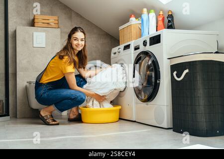 Young woman smiling while doing laundry in modern home interior Stock Photo