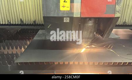 CNC laser cutting machine working with sheet metal with sparks at factory Stock Photo