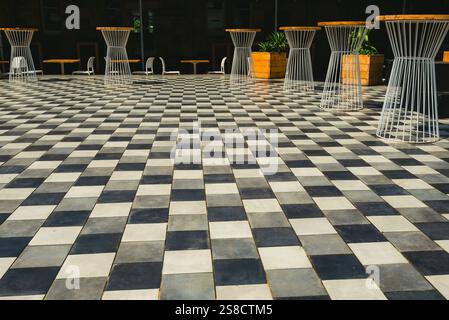 An outdoor bar area with a checkerboard floor (repeating pattern) and splashes of yellow colour Stock Photo