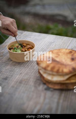 Winter spiced chicken soup and flatbreads cooked over fire at the Hidden Hut cafe at Porthcurnick Beach, Cornwall, UK Stock Photo