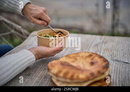Winter spiced chicken soup and flatbreads cooked over fire at the Hidden Hut cafe at Porthcurnick Beach, Cornwall, UK Stock Photo