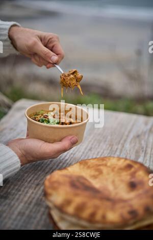 Winter spiced chicken soup and flatbreads cooked over fire at the Hidden Hut cafe at Porthcurnick Beach, Cornwall, UK Stock Photo