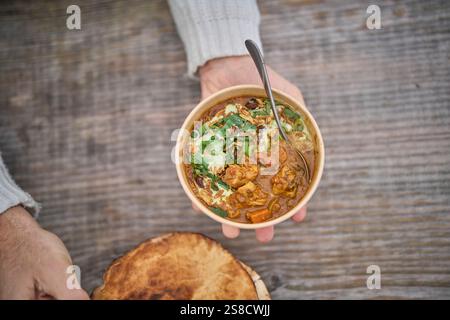 Winter spiced chicken soup and flatbreads cooked over fire at the Hidden Hut cafe at Porthcurnick Beach, Cornwall, UK Stock Photo