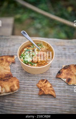 Winter spiced chicken soup and flatbreads cooked over fire at the Hidden Hut cafe at Porthcurnick Beach, Cornwall, UK Stock Photo