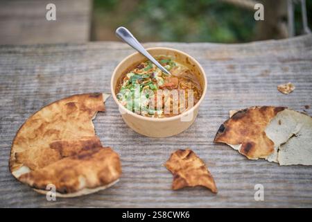 Winter spiced chicken soup and flatbreads cooked over fire at the Hidden Hut cafe at Porthcurnick Beach, Cornwall, UK Stock Photo