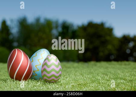 Colorful Easter eggs on green grass under a clear blue sky. 3d rendering Stock Photo